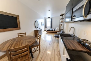 A modern kitchen with a central island, built-in appliances, and a dining area with a round table and chairs. - Welcome to Downtown! (Québec)