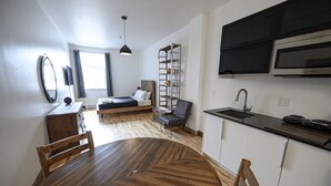Et lille køkken med hvide skabe, en sort bordplade og en indbygget mikroovn.