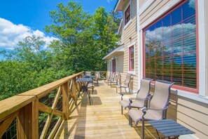 A wooden deck with outdoor furniture, a railing, and a building with large windows. - Top Property In Snowshoe 8 Br Nwr Rd 11 Luxury Home (Snowshoe)
