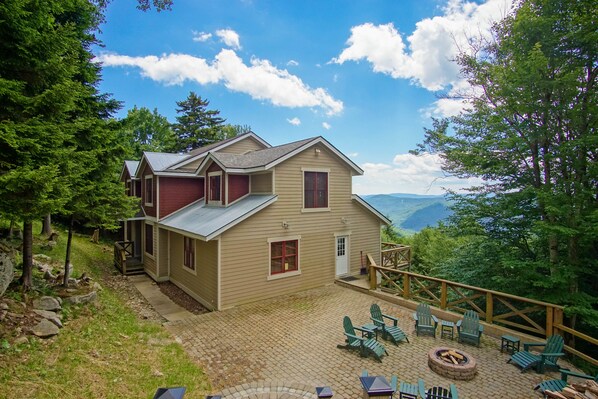 A two-story lodge with a patio area featuring Adirondack chairs and a fire pit. - Top Property In Snowshoe 8 Br Nwr Rd 11 Luxury Home (Snowshoe)