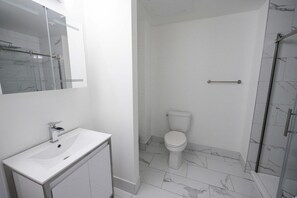 A bathroom with a white sink, a toilet, and a glass shower enclosure.