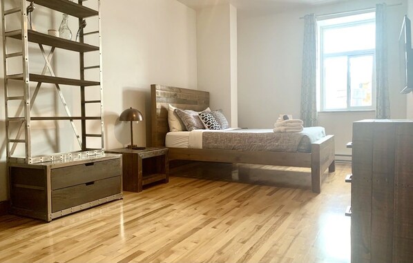 A bedroom with a wooden bed, a nightstand, a dresser, and a metal shelving unit.