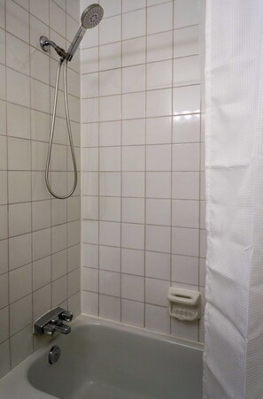 A bathroom with a bathtub, a showerhead, and a toilet. - Loft douillet au centre-ville ! (Québec)
