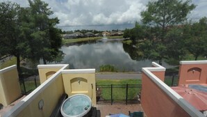 A view from a balcony overlooking a lake with a hot tub and an umbrella. - Terra Verde 70 (Kissimmee)