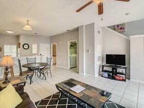 A spacious living room with a dining area, a kitchen in the background, and a TV on a stand. - Terra Verde 70 (Kissimmee)