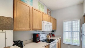 A modern kitchen with wooden cabinets, a microwave, a coffee maker, and a refrigerator. - Terra Verde 70 (Kissimmee)