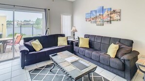A living room with two dark sofas, a glass coffee table, and a ceiling fan. - Terra Verde 70 (Kissimmee)