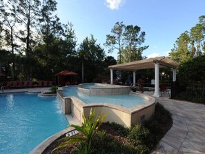 A swimming pool with a circular design, a covered seating area, and a pavilion. - Champions Gate 8219 (Davenport)