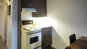 A compact kitchen with a stove, oven, and dark cabinets.