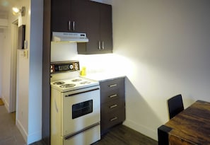 A compact kitchen with a stove, oven, and dark cabinets.