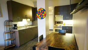 A modern kitchen with wooden cabinets, a dartboard, and a dining table with chairs. - Intimate loft in the heart of the city (Québec)