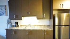 A kitchen with wooden cabinets, a stainless steel refrigerator, and a sink. - Intimate loft in the heart of the city (Québec)
