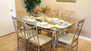 A dining table set with plates, a vase with flowers, and chairs with patterned cushions. - Lakeside in Clermont (Clermont)
