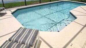 A swimming pool with a view of a lake, surrounded by a fence and featuring a lounge area with striped cushions. - Lakeside in Clermont (Clermont)