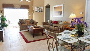 A living room with two sofas, a coffee table, and a dining area with a table set for four. - Lakeside in Clermont (Clermont)