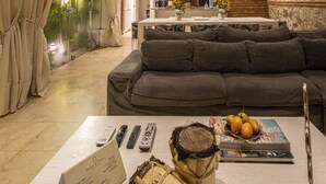 A spacious living area with a modern design, featuring a large gray sofa, a coffee table with remote controls and a magazine, and a decorative wooden centerpiece. - Santos de Piedra Exclusive Home (Provincia de Cartagena)