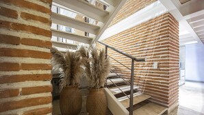 A staircase with a brick wall and a metal railing, leading to an upper floor. There are two large woven baskets on the floor near the staircase. - Santos de Piedra Exclusive Home (Provincia de Cartagena)