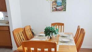 Ein Esstisch mit sechs Holzstühlen, einer Vase mit Grünpflanzen und einem Gemälde an der Wand.