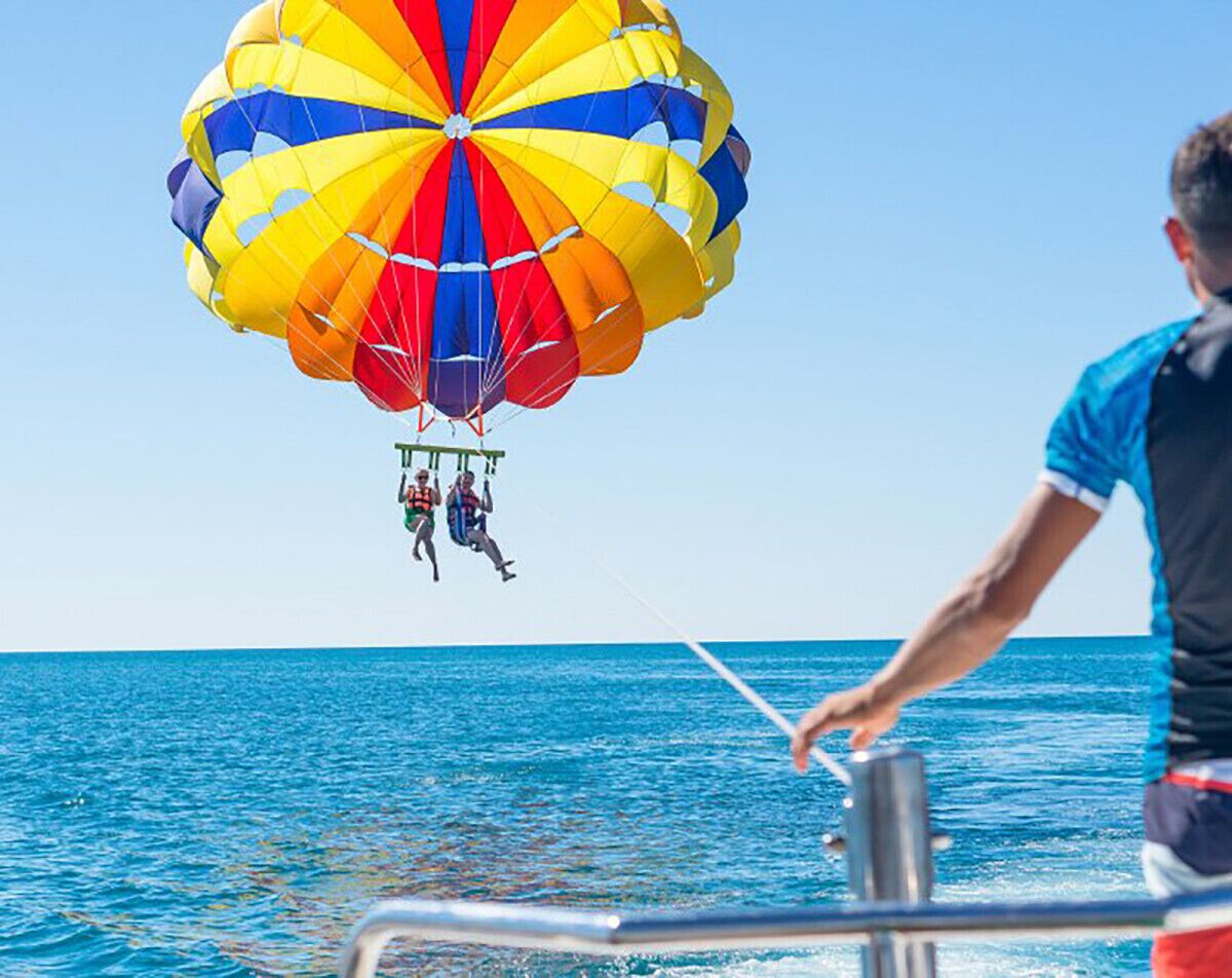 A person parasailing over the ocean with a colorful parachute.