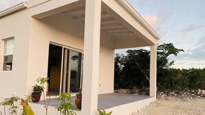 Una casa moderna con porche cubierto, puerta corrediza de vidrio y plantas en macetas.