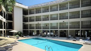 A multi-story hotel with a swimming pool, outdoor seating, and a palm tree. - Awesome Condo! King size bed! Updated! Ocean Views! 2 Bikes! #218 Great Reviews! (Hilton Head Island)