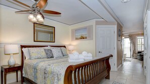 A bedroom with a wooden bed, a ceiling fan, and a view of the hallway. - Awesome Condo! King size bed! Updated! Ocean Views! 2 Bikes! #218 Great Reviews! (Hilton Head Island)