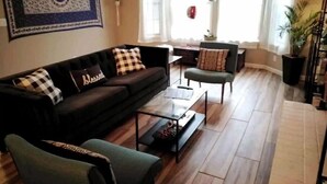 Ein Wohnzimmer mit Sofa, Sessel, Couchtisch und einer dekorativen Wandgestalt.