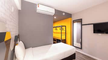 A modern hotel room with a bed, air conditioning unit, and a TV on the wall.