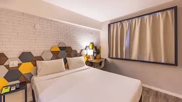 A hotel room with a bed, a nightstand, a lamp, and a wall with a geometric pattern.