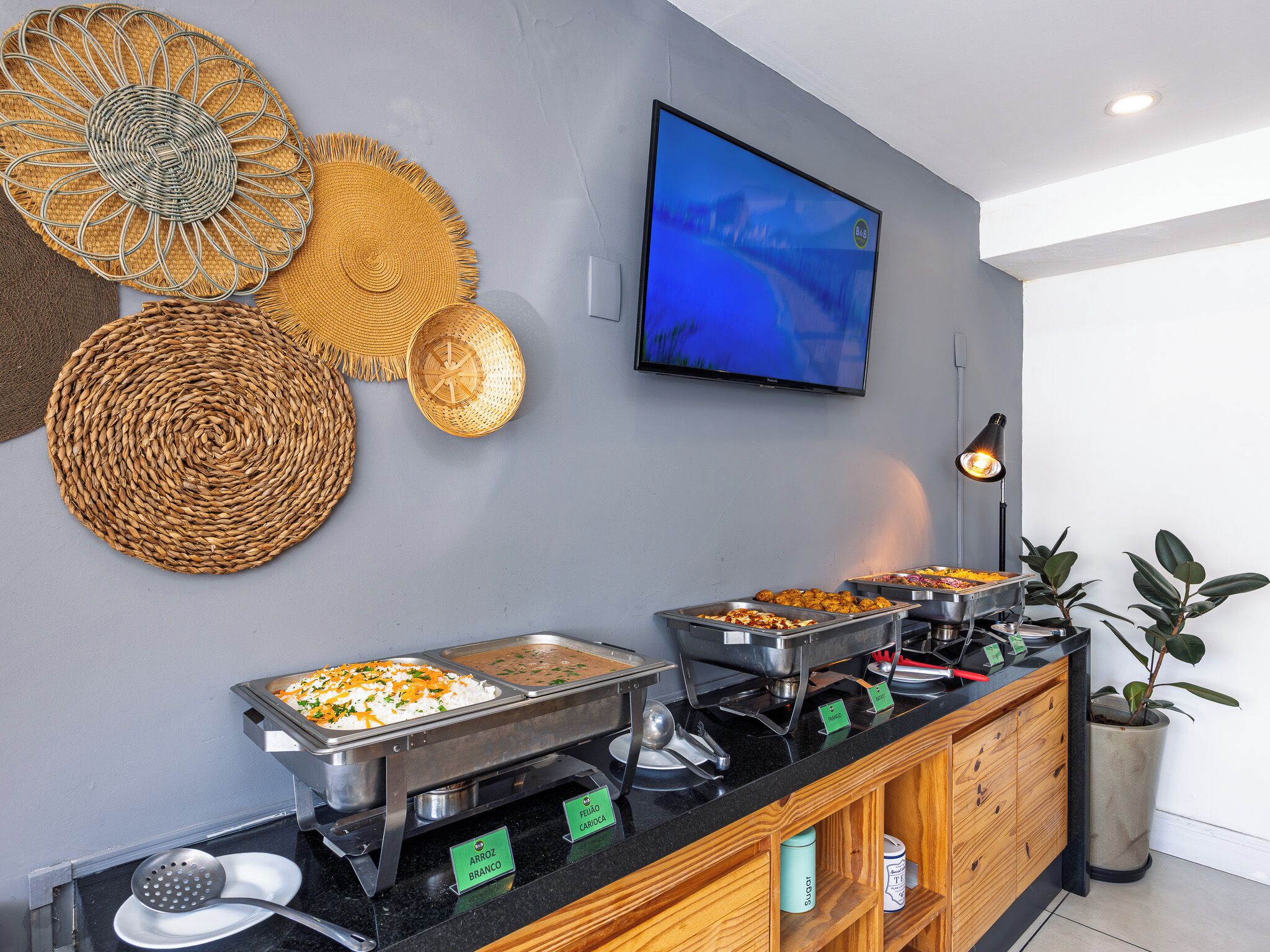 A buffet setup with labeled food stations, a television, and decorative wall art.