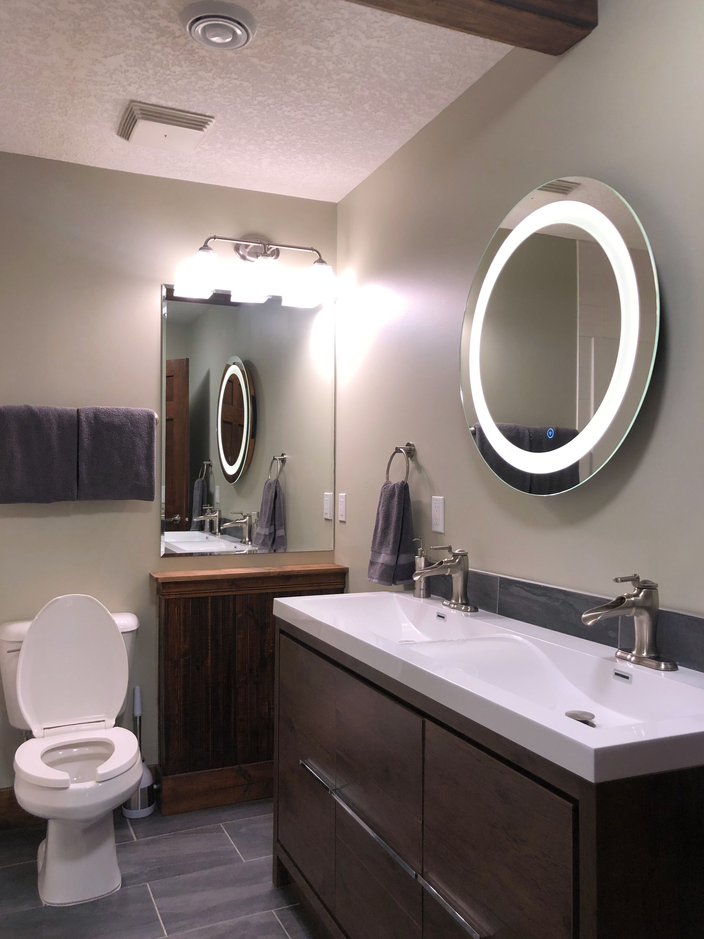 A modern bathroom with a white toilet, a vanity with a mirror, and a sink with a faucet.