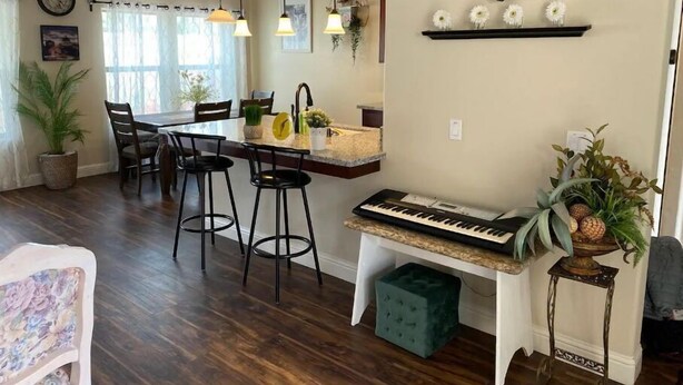 A dining area with a kitchen island, bar stools, and a piano. - Brand New Home Close to Sequoia /w Tub & Games (Visalia)