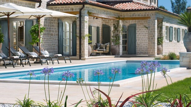 A poolside area with lounge chairs and umbrellas, a stone building with arched windows, and a clear blue pool. - Villa Terra Verde with Pool (Kanfanar)