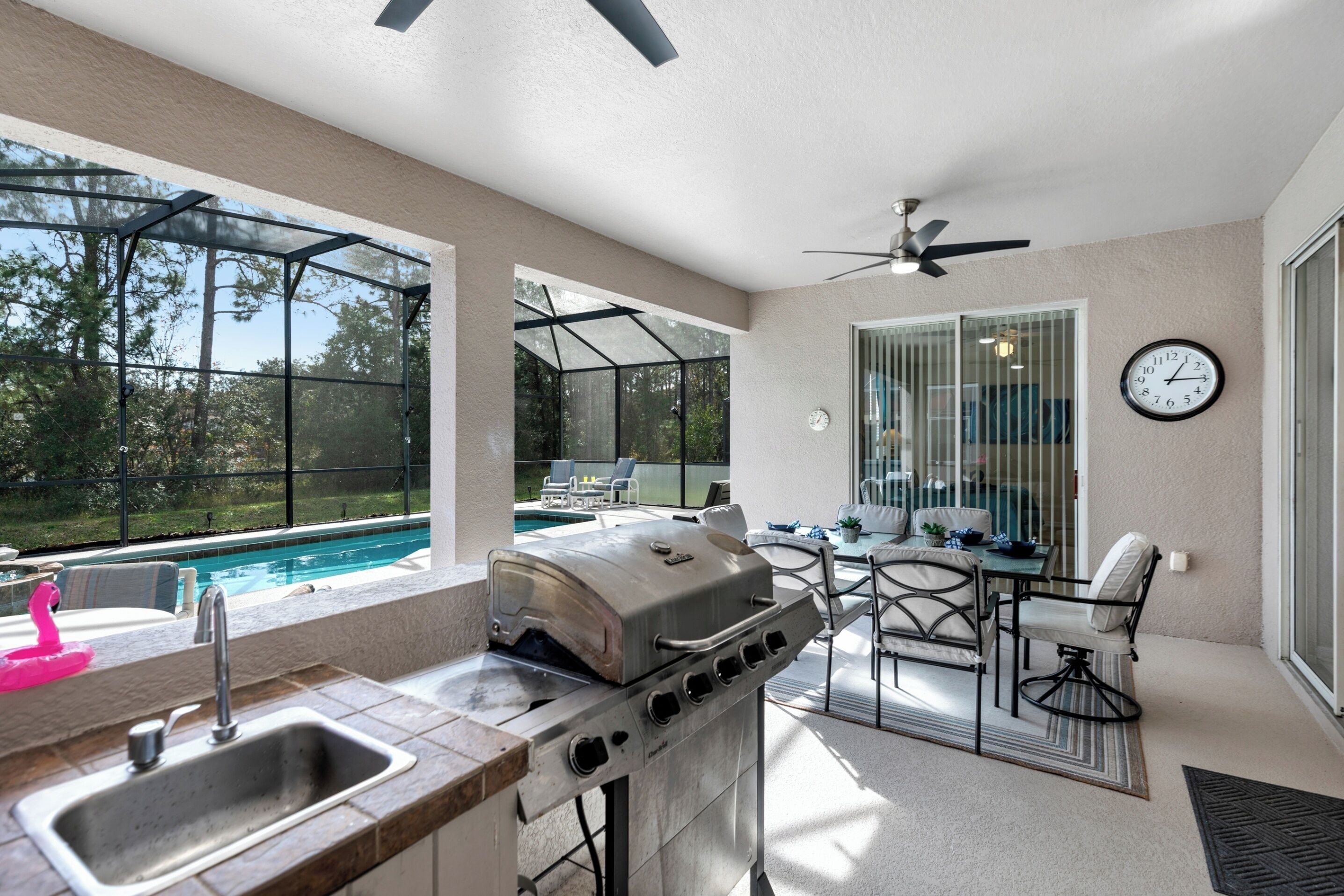 A patio with a grill, dining area, and a view of a swimming pool.