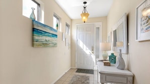 A hallway with a white door, a painting, a lamp, and a small table with decorative items. - Gorgeous Davenport 5 Bed Villa With Pool Hot Tub (Davenport)