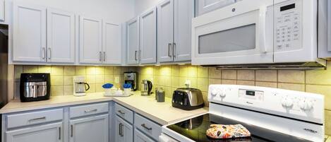 Une cuisine avec des meubles de couleur bleu clair, un four à micro-ondes blanc, une cuisinière et un grille-pain.