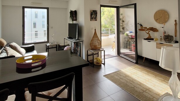 Amplia sala de estar con una mesa de comedor, sillas, televisor y vista a un balcón exterior a través de un ventanal.