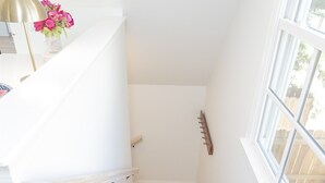Un escalier aux murs blancs et aux marches en bois menant à un palier.