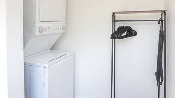 Un espace buanderie équipé d’un lave-linge, d’un sèche-linge et d’un étendoir.