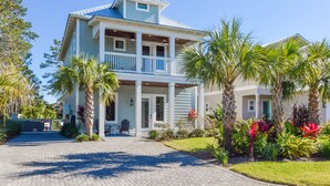 A two-story house with a balcony, surrounded by palm trees and a well-maintained garden. - Sea Glass Cottage ~ Private Pool ~ Private Beach Access ~ Golf Cart Included! (Miramar Beach)