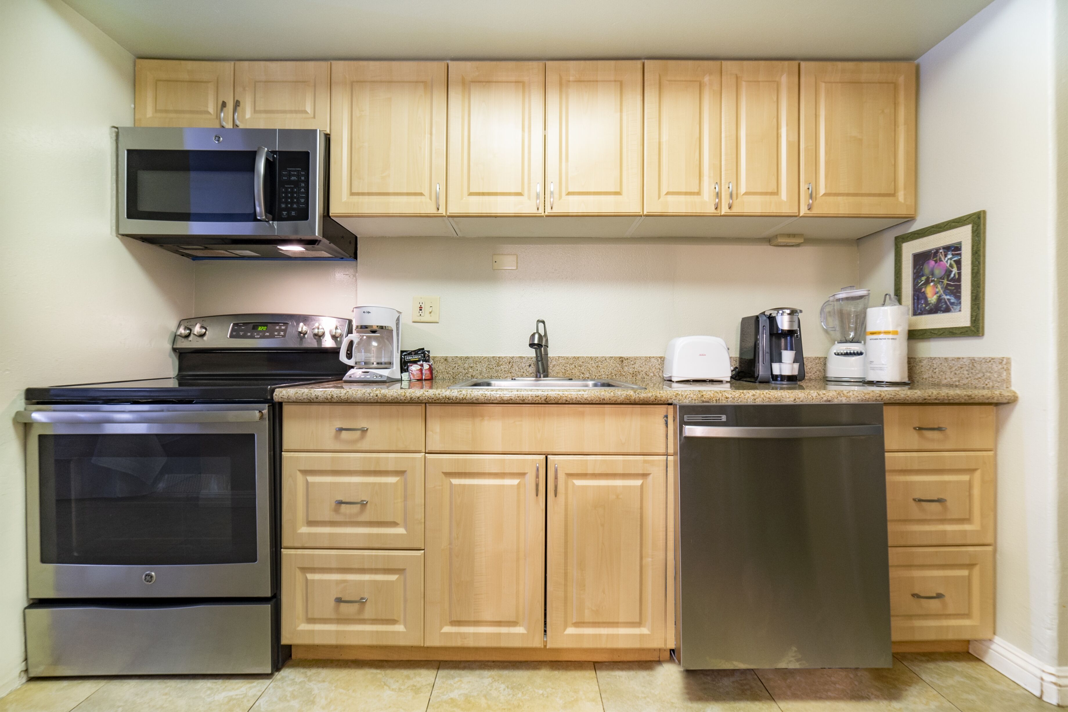 A modern kitchen with stainless steel appliances, wooden cabinets, and a granite countertop.