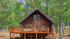 Une cabane en bois dotée d’une terrasse, entourée d’arbres.