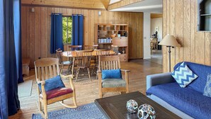 A wooden interior with a dining area, a sofa, and a bookshelf. - Cozy woodland cabin w/ hot tub & deck (Berkeley Springs)