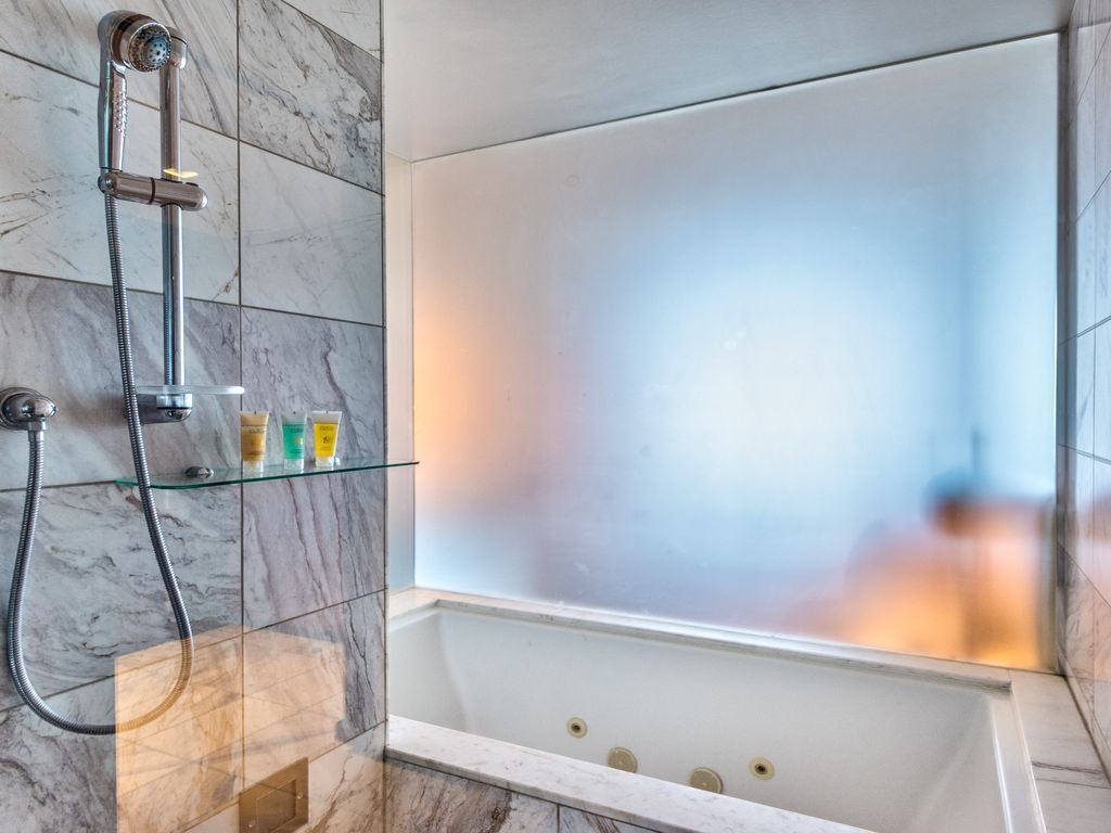 Ein modernes Badezimmer mit einer Glasablage für Toilettenartikeln, einer Dusche mit Duschbrause und einer Badewanne mit Glastrennwand.