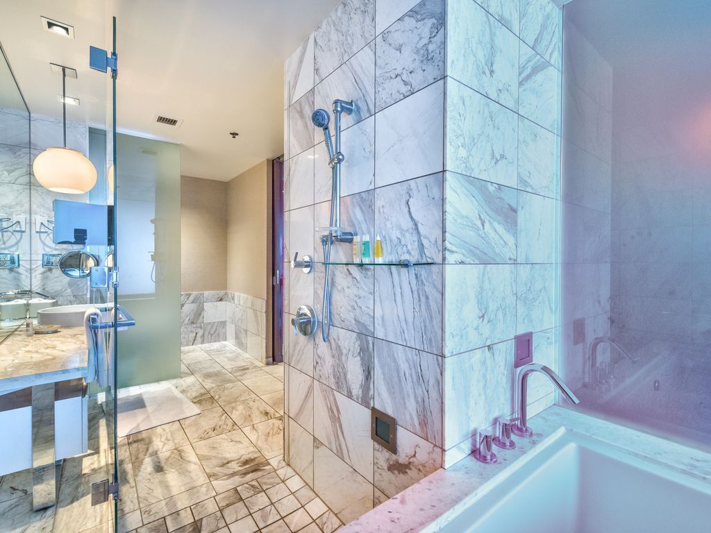 Une salle de bain moderne avec des carreaux de marbre, une douche en verre et un meuble-lavabo avec un miroir.