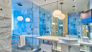 A modern bathroom with a glass-enclosed shower, a marble vanity, and a large mirror.