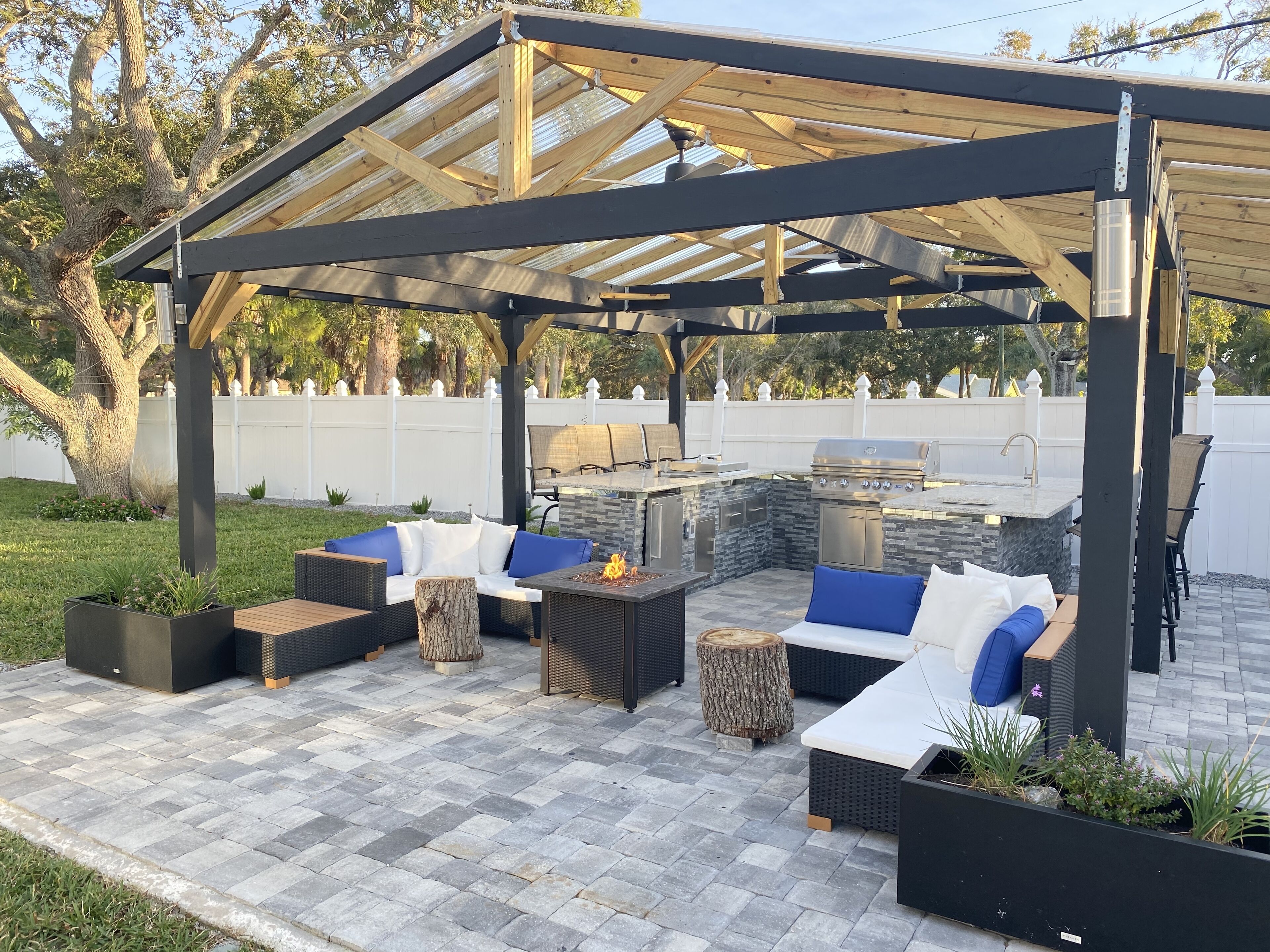 Een terras buiten met een pergola, zithoek en ingebouwde barbecue.