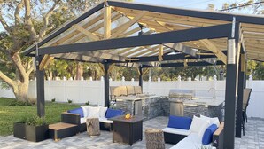 An outdoor patio with a pergola, seating area, and built-in grill. - Bright & Airy St. Pete Home w/ Outdoor Living (St. Petersburg)