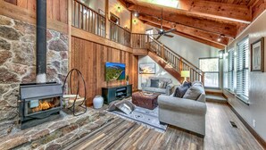 A spacious living area with a stone fireplace, a wooden staircase, and a cozy seating area with a sofa and a coffee table.