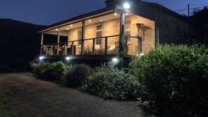 A two-story house with a covered porch, a stone exterior, and a well-lit interior. - Historic Georgian Stone Built Cottage (Saint Albans)